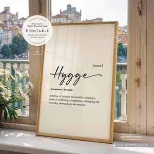 Puede incluir: Arte de pared imprimible con marco dorado y fondo blanco. La palabra "Hygge" está escrita en cursiva negra con una definición debajo. La definición dice: "[nombre] /pronunciar/ hue-guh una sensación de comodidad y confort, creando una sensación de bienestar, satisfacción, celebrando lo cotidiano, perteneciendo al momento"