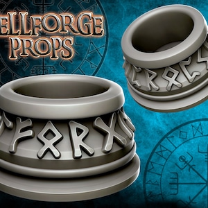 Peut inclure: Deux anneaux décoratifs gris cylindriques avec des runes en relief autour du bord supérieur. Les anneaux sont faits d'un matériau lisse et mat. Le texte "HELLFORGE PROPS" est visible en arrière-plan.