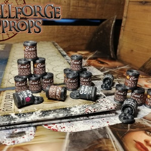 Op de afbeelding: Een verzameling miniatuur blikjes in zwart en bruin met de tekst "Carl's Chocolate Pudding" en "Carl's Cook 72" erop gedrukt. De blikjes zijn in een piramidevorm op een zwart-wit speelbord gerangschikt.