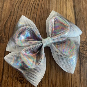 May include: A large white and iridescent silver bow with a glittery centre. The bow is made of a shiny, textured fabric.