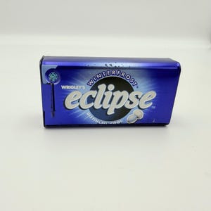 May include: A blue metal container of Wrigley's Eclipse Winterfrost mints. The container has the brand name and product name in white lettering. The container is rectangular with rounded edges and a hinged lid.
