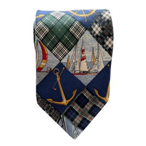 May include: A necktie featuring a diamond-patterned design with alternating sections of green and blue plaid, illustrations of sailboats on water, and golden anchors. The fabric displays a textured weave with nautical motifs including a ship wheel.