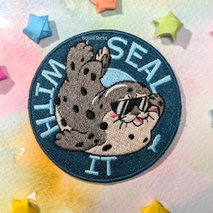 Peut inclure: Un patch brodé bleu et blanc avec un phoque de dessin animé portant des lunettes de soleil et le texte "I'm Seal It" autour du bord.