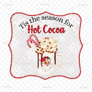 May include: A red and white sign with a white background and red glitter trim. The sign says "Tis the season for Hot Cocoa" and features a white mug with a Santa Claus face, filled with hot cocoa, marshmallows, and chocolate chips. Candy canes are sticking out of the top of the mug.