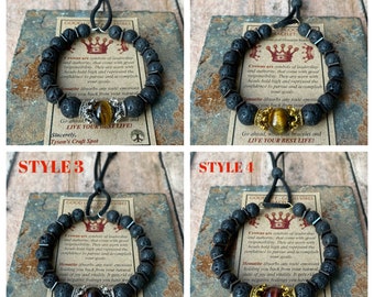 Op de afbeelding: Vier verschillende stijlen lava-armbanden met tijgeroog kralen, gouden accenten en een kroonbedel. De armbanden worden getoond op een houten oppervlak met een kaart waarop "Good Vibes Bracelet" staat en een beschrijving van de betekenis van de armband.