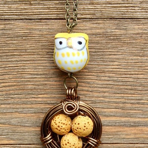 K&ouml;nnte beinhalten: Eine Halskette mit einem gelben Eulenschmuckst&uuml;ck und einem drahtgewickelten Nestanh&auml;nger mit drei gelben Lavasteinen.