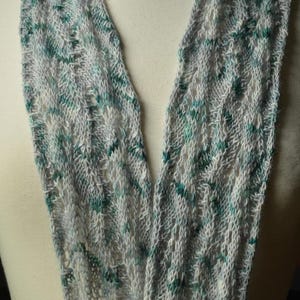 May include: A gray and teal knitted scarf with a lacy pattern.