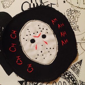May include: A black and white embroidered patch featuring a hockey mask and the words "CH CH CH" and "AH AH AH AH" in red thread.