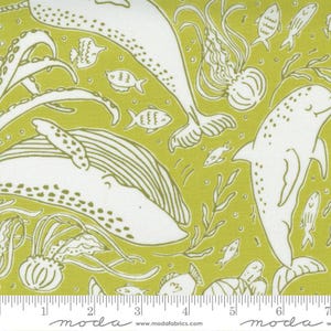 May include: Light green fabric featuring a white marine life pattern. The design includes whales, dolphins, fish, and jellyfish. The word "moda" is printed at the bottom, along with a website address. The pattern repeats across the fabric.