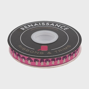 Puede incluir: Un carrete de cinta decorativa con fondo rosa y un patrón repetido de setas moradas y blancas. El carrete es negro y tiene el texto "Renaissance Ribbons & Trims".