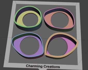 May include: Four colorful, overlapping, ring-shaped cookie cutters. The cutters are in the shape of an eye, with a smaller circle in the center. The colors are green, blue, orange, and pink.