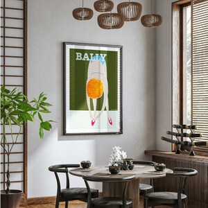 May include: A framed poster with a green background and a woman in a blue swimsuit diving into a pool of orange water. The poster has the word "BALLY" printed in white letters at the top.