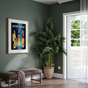 Pu&ograve; includere: Un poster incorniciato con un design grafico colorato dello skyline di New York City. Il poster &egrave; appeso a una parete verde salvia. Una palma in vaso si trova nell'angolo della stanza. Una panca di legno con una coperta &egrave; in primo piano.