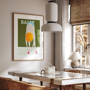 May include: A framed poster with a green background and a woman in a blue swimsuit bending over with the word "BALLY" in white letters at the top.