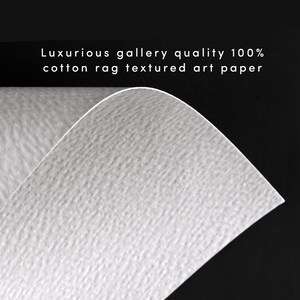 May include: Close-up of a white, textured art paper. The paper has a subtle, rough texture, similar to the feel of cotton rag. The text "Luxurious gallery quality 100% cotton rag textured art paper" is printed at the top of the image.