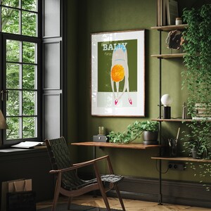 May include: A framed poster with a green background and a person in a blue swimsuit bending over with the word "BALLY" in white letters at the top.