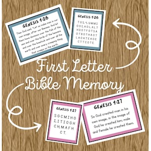 May include: A wooden background with four cards featuring Bible verses and the title "First Letter Bible Memory." The cards have text from Genesis 1:26 and 1:27. The text is in black and the cards have blue and pink borders.