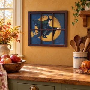 May include: A rectangular wall art piece featuring a dark brown wooden window frame overlaying a painting of a witch in a black hat and cloak flying on a broomstick against a large yellow full moon and a dark blue night sky with a small bat.