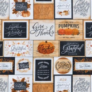May include: A digital print fabric featuring a repeating pattern of various signs with autumnal themes. The signs have a rustic wood look and feature phrases like "Give Thanks", "Gather Together", "Grateful", and "Pumpkins".