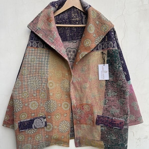 May include: A long-sleeved jacket featuring a patchwork design with various floral and geometric patterns in shades of purple, orange, pink, and green. The garment has a wide collar, two front pockets, and a tag labeled LARESSA GIFTS.