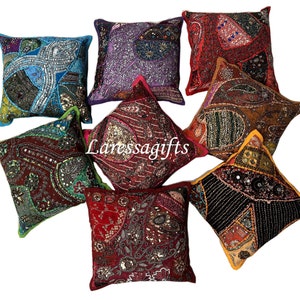 Può includere: Nove cuscini quadrati colorati con ricami intricati e decorazioni. I cuscini sono realizzati con diversi tessuti e presentano un mix di paillettes, perline e altri elementi decorativi.