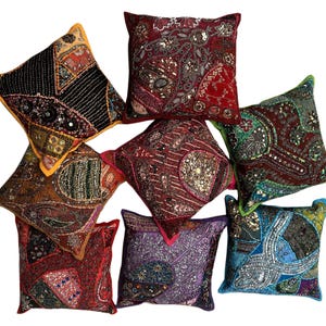 May include: Eight decorative throw pillows with colorful embroidered patterns and sequins. The pillows are made of fabric and have a variety of colors, including red, green, blue, purple, and gold.