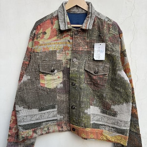 Pode incluir: Uma jaqueta de manga comprida com botões, apresentando um design de patchwork multicolorido com vários padrões em tons de verde-oliva, castanho, laranja e cinzento. A jaqueta inclui dois bolsos no peito com abas, gola e uma etiqueta branca LR SS G FTS.