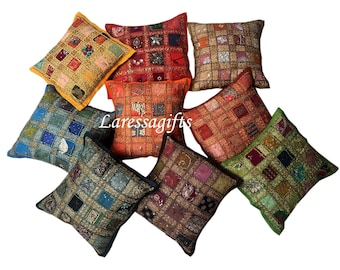 May include: Assortment of eight colorful square throw pillows with intricate patchwork designs and embellishments. The pillows are made of fabric with a variety of textures and patterns, including sequins, embroidery, and beads. The pillows are arranged in a circular pattern on a white background.