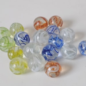 Puede incluir: Una colección de canicas de vidrio en varios colores, incluyendo verde, azul, blanco y naranja. Las canicas tienen patrones de color en espiral en su interior.