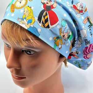 May include: Blue scrub hat with a white polka dot pattern and a colorful Alice in Wonderland print featuring characters like the Queen of Hearts, Mad Hatter, and Alice. The text "We're all mad here" is printed on the hat.