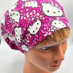 May include: Pink and white scrub hat with a repeating pattern of Hello Kitty faces and pink hearts.