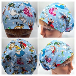 May include: Blue surgical scrub hat with a white polka dot pattern and colorful Alice in Wonderland characters. The hat features the text "We're all mad here".