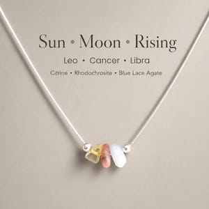 May include: A silver necklace with three gemstones: citrine, rhodochrosite, and blue lace agate. The necklace features the text "Sun * Moon * Rising" and the zodiac signs Leo, Cancer, and Libra.