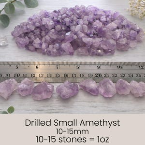 May include: A collection of small, drilled amethyst crystals in varying shades of purple. The image includes a ruler for scale, with individual stones measuring 10-15mm. The text indicates that 10-15 stones equal 1 ounce.