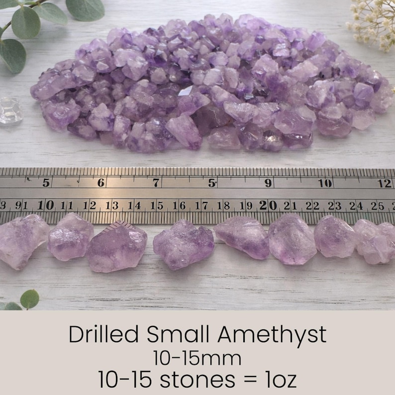 May include: A collection of small, drilled amethyst crystals in varying shades of purple. The image includes a ruler for scale, with individual stones measuring 10-15mm. The text indicates that 10-15 stones equal 1 ounce.