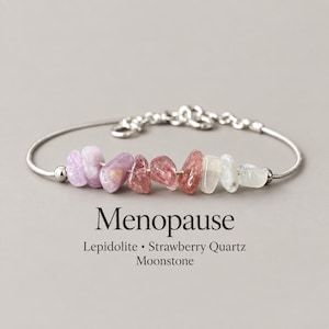 May include: A silver-toned metal chain bracelet featuring a row of raw, tumbled gemstone chips including purple lepidolite, pink strawberry quartz, and white moonstone. The text "Menopause" and "Lepidolite • Strawberry Quartz Moonstone" is printed below.