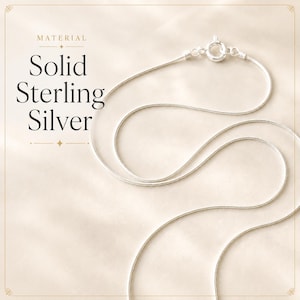 May include: A silver necklace with a fine chain and a circular clasp. The image includes the text "Solid Sterling Silver" and "Material" in a serif font, set against a cream background.