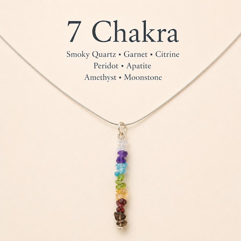 Pu&ograve; includere: Una collana d'argento con un ciondolo con sette pietre preziose colorate, che rappresentano i sette chakra. Le pietre sono disposte in una linea verticale, con una variet&agrave; di colori tra cui viola, blu, verde, giallo e rosso. Il testo "7 Chakra" &egrave; in alto.