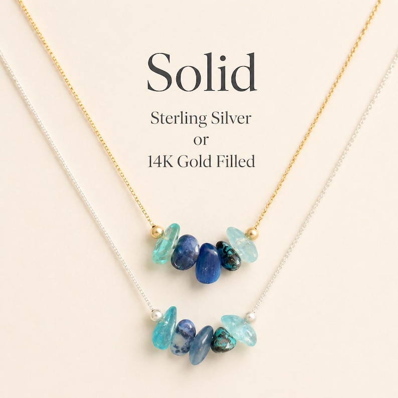 May include: Two necklaces with blue gemstone pendants. One necklace is gold-colored, the other is silver-colored. The text "Solid" and "Sterling Silver or 14K Gold Filled" are displayed above the necklaces.