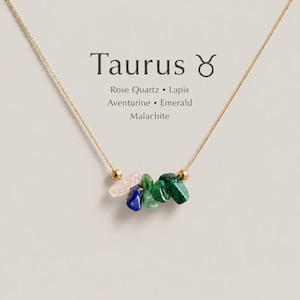 K&ouml;nnte beinhalten: Eine goldene Halskette mit einer Ansammlung roher Edelstein-Chips, darunter Rosenquarz, Lapislazuli, Aventurin, Smaragd und Malachit. Der Text Taurus mit dem Symbol und die Liste der Steine sind auf der Anzeigekarte &uuml;ber dem Anh&auml;nger gedruckt.