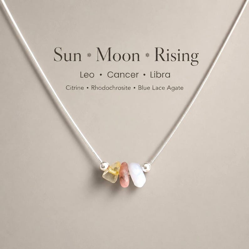 May include: A silver necklace with three gemstones: citrine, rhodochrosite, and blue lace agate. The necklace features the text "Sun * Moon * Rising" and the zodiac signs Leo, Cancer, and Libra.