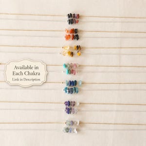 May include: A collection of delicate necklaces, each featuring a strand of small, colorful gemstones. The gemstones are arranged in a row, with a variety of colors including black, orange, yellow, blue, and purple. The text "Available in Each Chakra, Link in Description" is also visible.