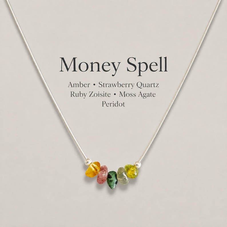 May include: A silver-tone chain necklace featuring five small, irregular tumbled gemstones in yellow, pink, green, and olive. Text above the stones reads: Money Spell, Amber, Strawberry Quartz, Ruby Zoisite, Moss Agate, Peridot.