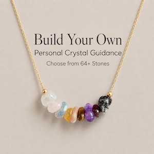 May include: A gold chain necklace featuring a row of nine multi-colored polished gemstone beads. The text "Build Your Own Personal Crystal Guidance Choose from 64+ Stones" is printed above the necklace, which is centered on a neutral background.