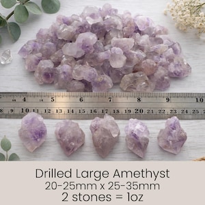 May include: A collection of raw, light purple amethyst crystals, some drilled, with a ruler for scale. The image includes text that reads "Drilled Large Amethyst 20-25mm x 25-35mm 2 stones = 1oz."