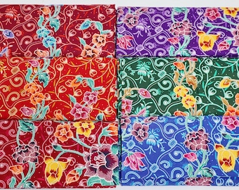 May include: Six fabric swatches featuring floral patterns in a variety of colours, including red, green, blue, and purple. The fabric has a traditional batik design.