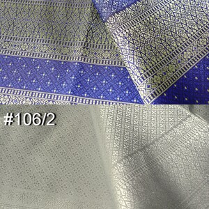 May include: Two pieces of fabric with intricate patterns. The top piece is a dark blue fabric with a gold and white pattern. The bottom piece is a light gray fabric with a gold pattern. The fabric is labeled #1 and #106/2.