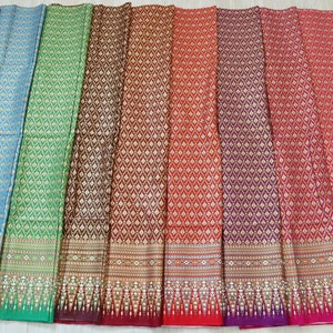 May include: Ten different fabric swatches with a repeating geometric pattern in gold and various colors, including purple, blue, green, brown, red, and black. The fabric has a woven texture and a decorative border.