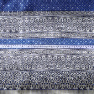 May include: A close-up of a blue and white patterned fabric with a white measuring tape across the middle. The fabric has a repeating pattern of small white flowers and a larger pattern of white flowers and leaves.