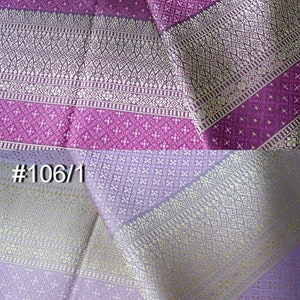 May include: Two pieces of fabric with a patterned design. The top piece is purple with a white pattern and the bottom piece is light purple with a gold pattern. The fabric is labeled #14 and #106/1.
